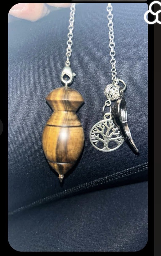 Pendule de radiesthésie en bois aux reflets d’œil-de-tigre, sur fond bleu nuit